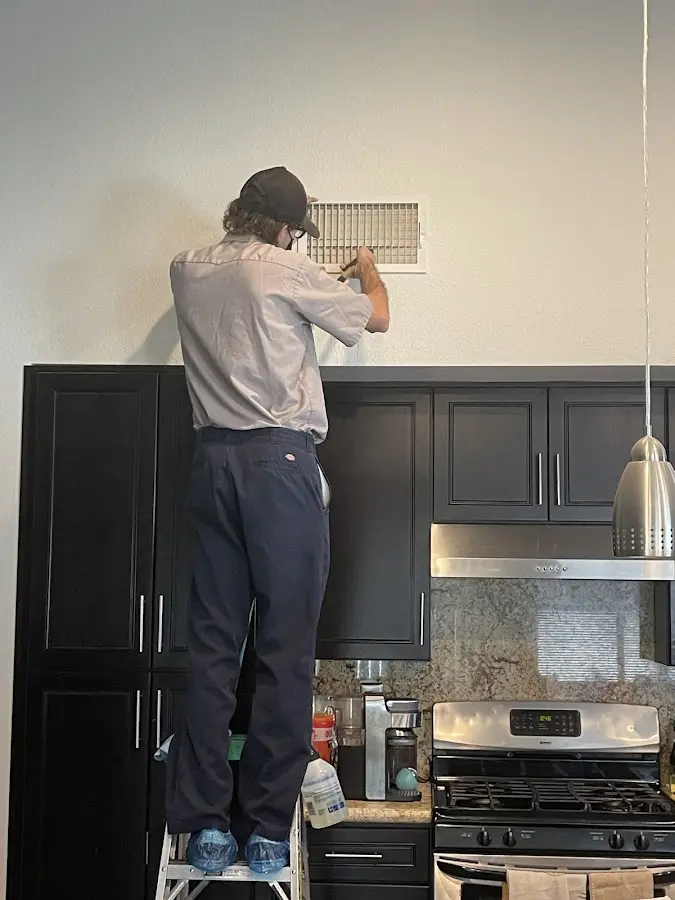Technician inspecting an air vent during HVAC service in Green